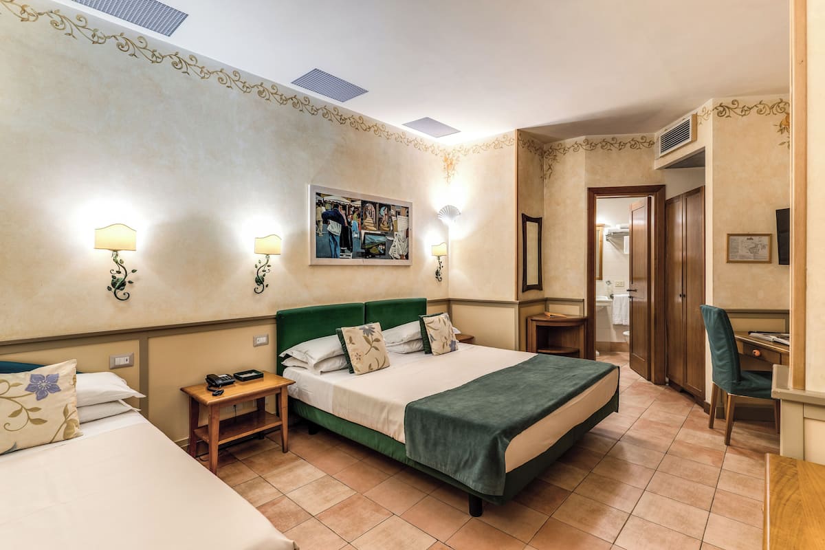 A hotel room with a large bed, bedside tables, a desk, and a chair.