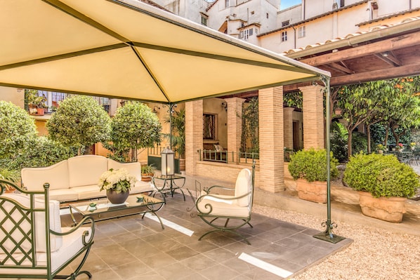 A covered outdoor seating area with a sofa, chairs, and a table.