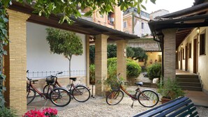 A courtyard with bicycles, a bench, and potted plants. - Hotel Santa Maria (Rome)