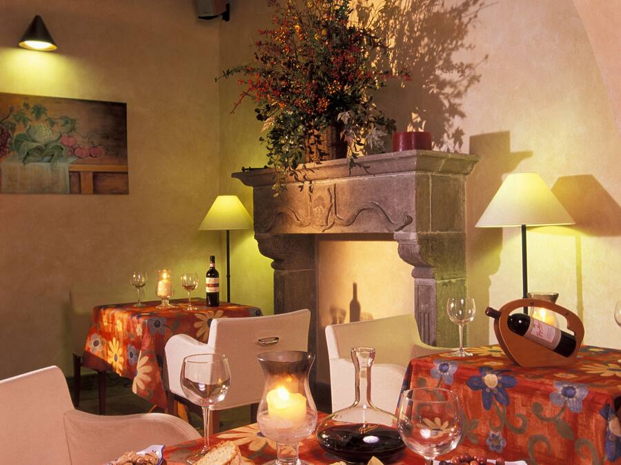 Un coin repas avec une table dressée pour deux personnes, où l’on trouve une variété de fromages, de noix et de pain.
