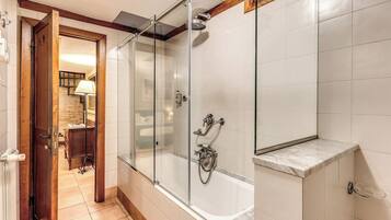 Un baño moderno con ducha de vidrio, lavamanos de mármol y toallero a la vista.