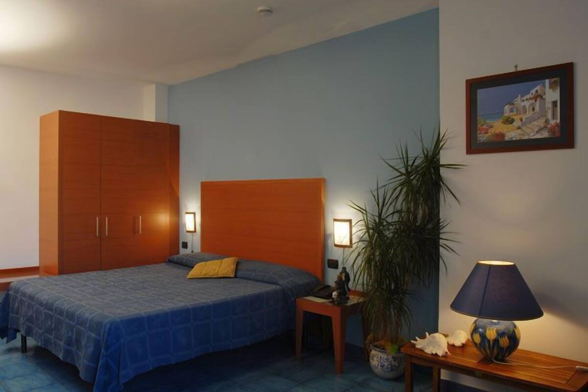Une chambre à coucher comprenant un lit, une table de chevet, une lampe et une grande armoire.