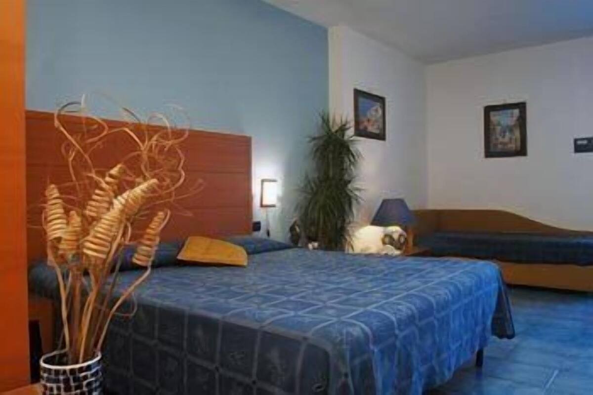 Une chambre à coucher avec un lit, une table de chevet, une lampe et une plante.
