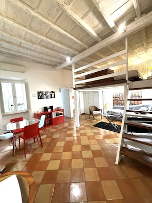 A room with a checkered floor, a bunk bed, a dining table with chairs, a red cabinet, and a bookshelf. - Boutique Hotel Anahi (Rome)
