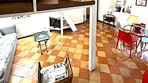 Um quarto com uma cama de solteiro, uma mesinha, uma cadeira, um sofá e uma lixeira.