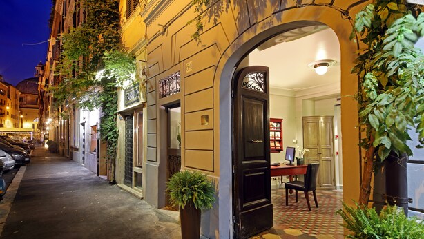Uma rua estreita com um edifício que apresenta uma porta preta e um pequeno espaço de escritório visível através de um arco.
