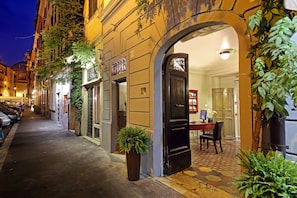 Una calle estrecha con un edificio que presenta una puerta negra y un pequeño espacio de oficina visible a través de un arco.