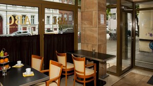 A restaurant with a table set for four, chairs, and a glass partition. - Pension ABC (Berlin)