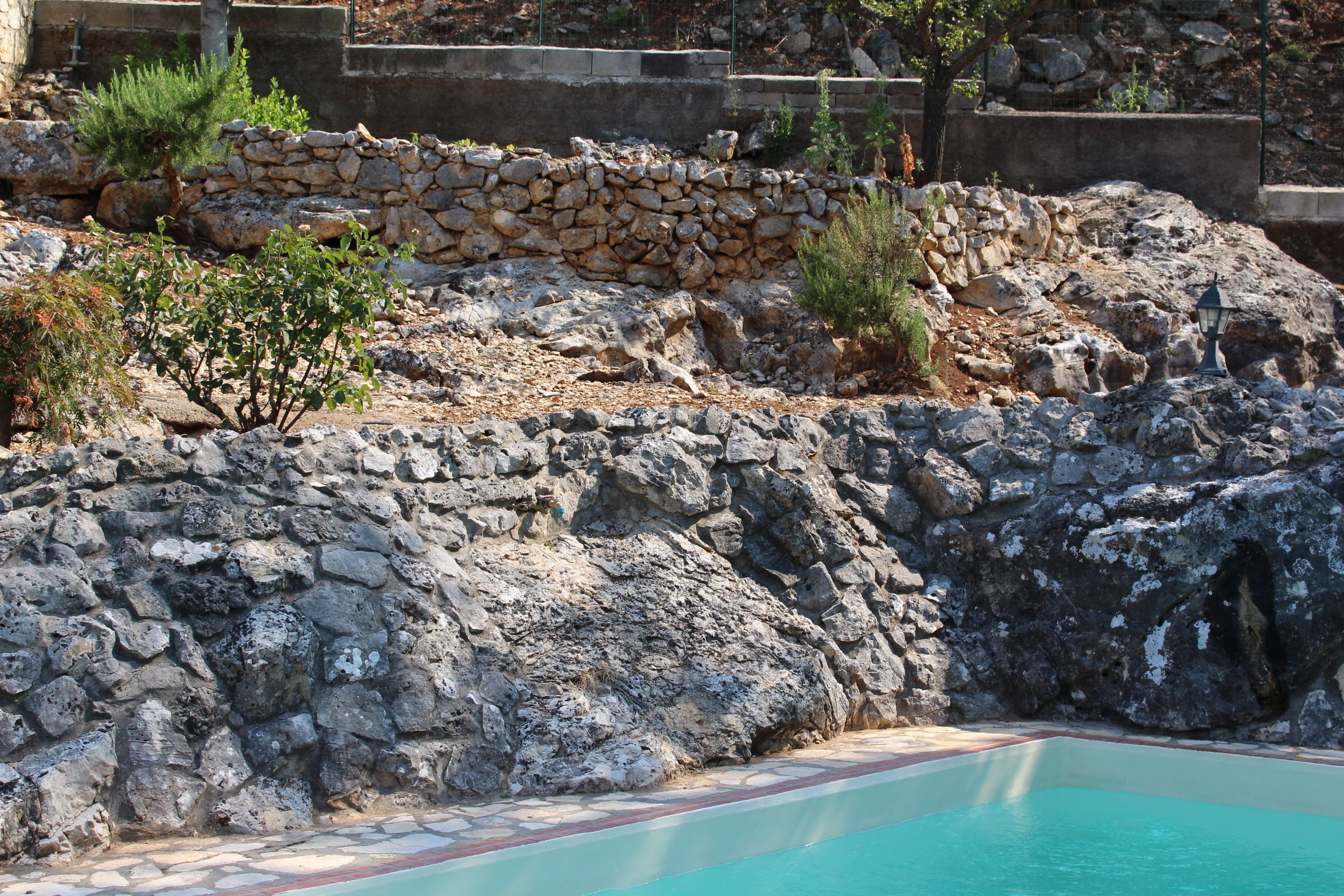 Un área de piscina con paredes de piedra y un suelo de baldosas.