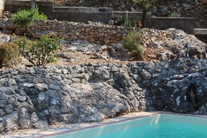 A pool area with stone walls and a tiled deck. - La Voce del Vento (Pastena)
