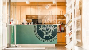 Un área de recepción con mostrador verde, armarios de madera y un logotipo sobre el mostrador.