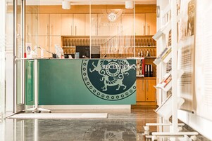 Un'area reception con un bancone verde, armadietti in legno e un logo sopra il bancone.