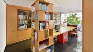 Una biblioteca con estanterías de madera, un escritorio con una computadora y una planta.