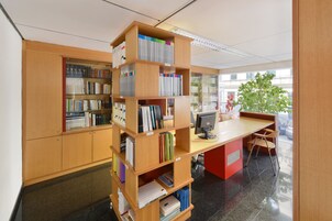 Una biblioteca con scaffali di legno, una scrivania con un computer e una pianta.