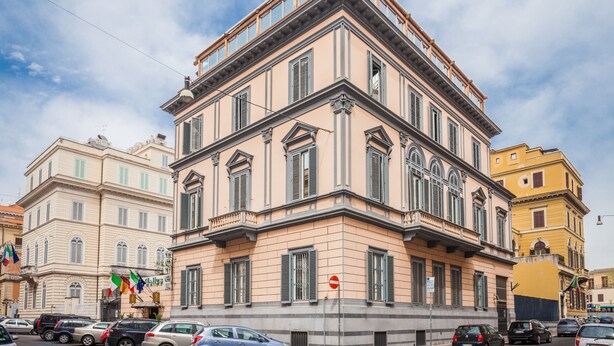 Un edificio de varios pisos con estilo arquitectónico clásico, que destaca por su entrada en esquina y grandes ventanales.