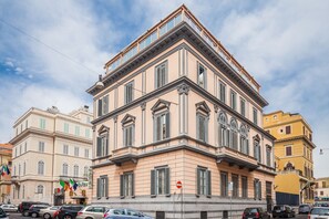 Un edificio de varios pisos con estilo arquitectónico clásico, que destaca por su entrada en esquina y grandes ventanales.