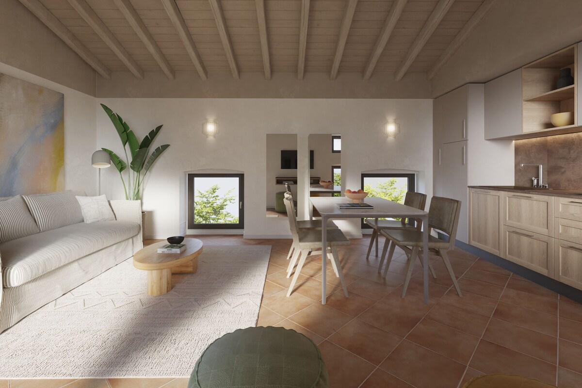 A spacious living room with a sofa, coffee table, and dining area. There is a large window and a view of the outdoors.