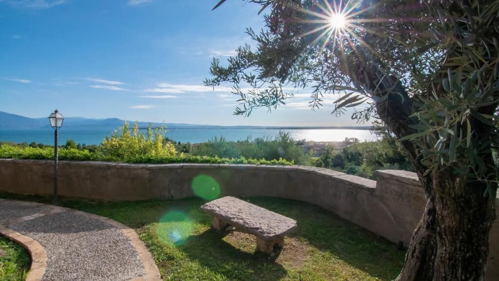 Eine Bank in einem Garten mit Blick auf das Meer und die Berge.