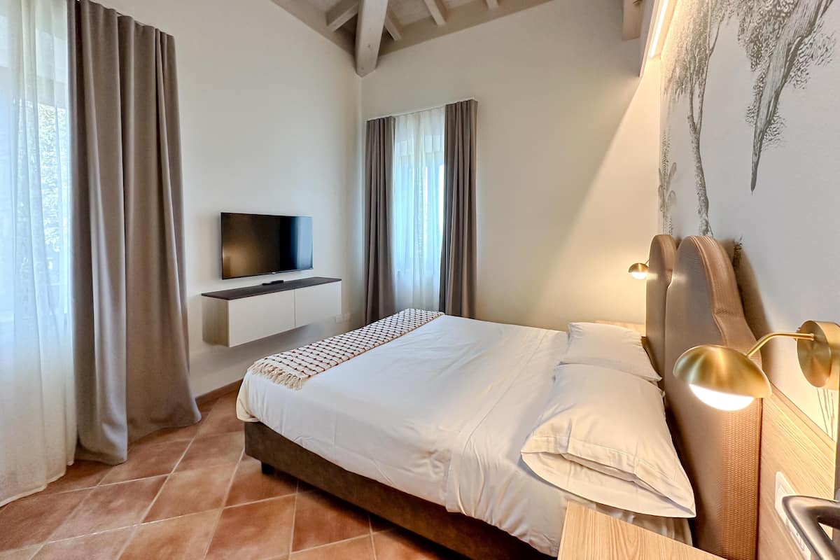 A bedroom with a bed, a mounted TV, and a headboard with lights.