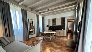 A spacious living area with a sofa, a dining table, and a kitchen in the background.