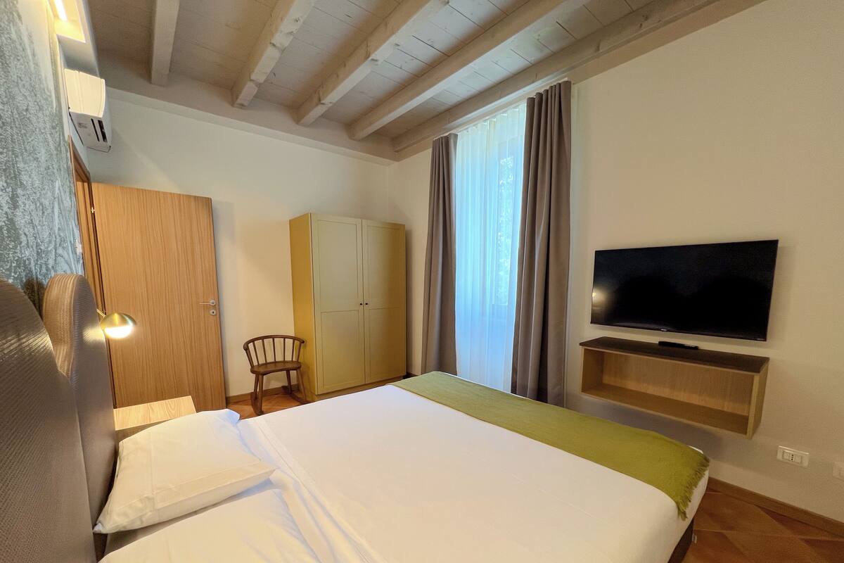 A hotel room with a bed, a television, a wardrobe, and a chair.