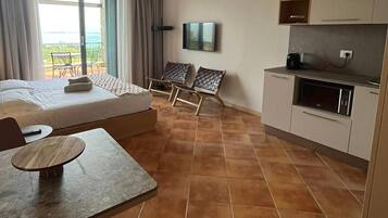 Ein Hotelzimmer mit einem Bett, einem Esstisch, zwei Stühlen, einem Fernseher und einer Küchenzeile.
