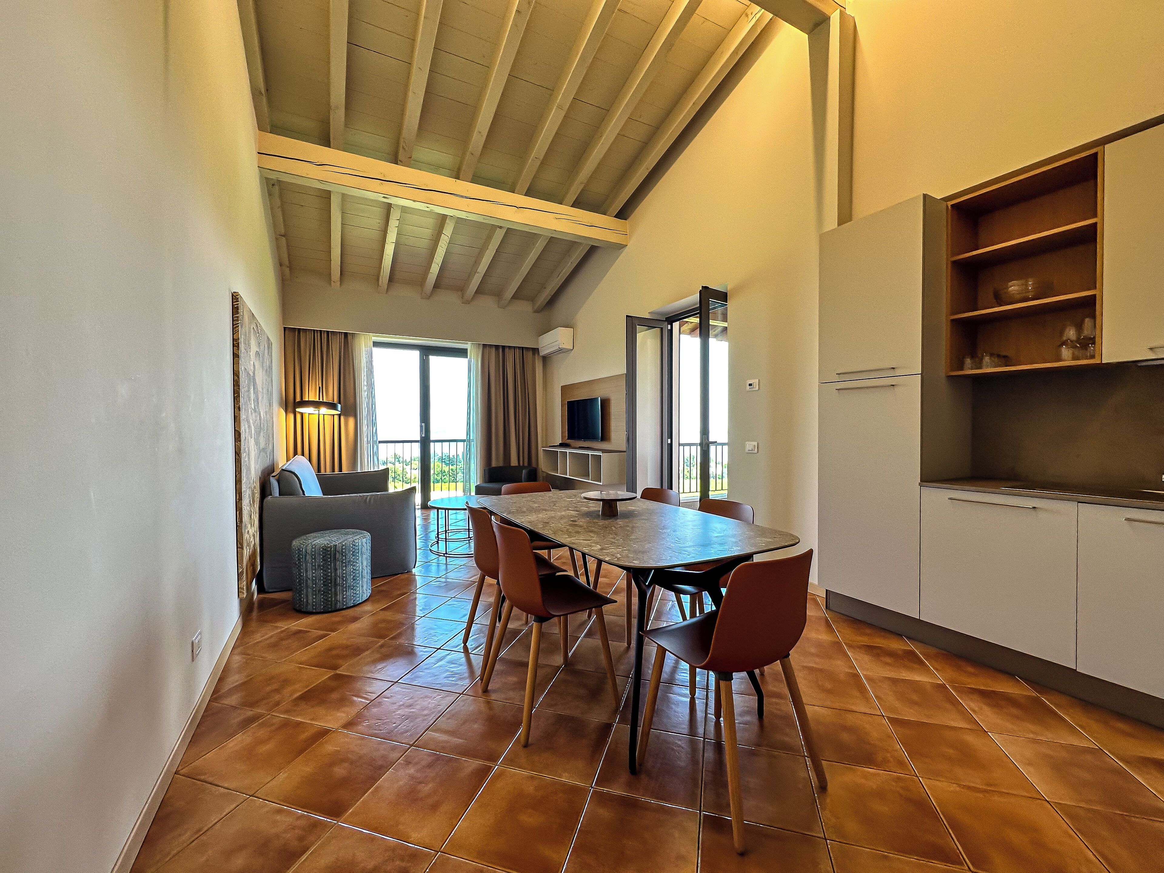 A modern kitchen with a dining area, a sofa, and a TV.