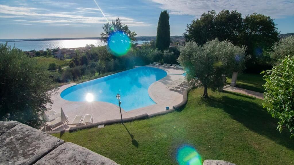 A swimming pool with a curved edge, surrounded by a well-maintained lawn and trees.