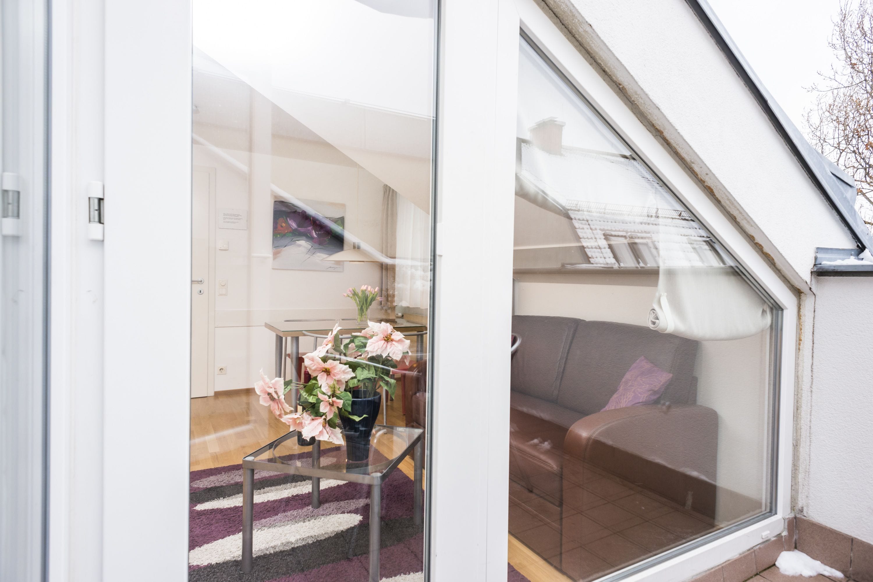 En modern inredning med en glasvägg, en soffa och ett bord med blommor.