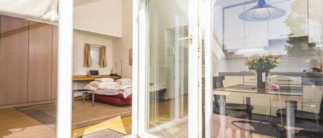 A modern kitchen with a glass door leading to a bedroom.