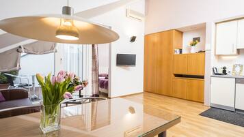 A modern kitchen with wooden cabinets, a glass dining table, and a vase of flowers.