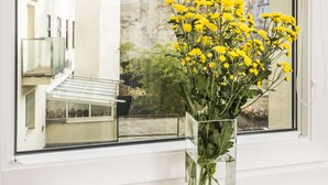 A clear view of a window with a vase of yellow flowers on a windowsill. - Appartements Ferchergasse (Vienna)