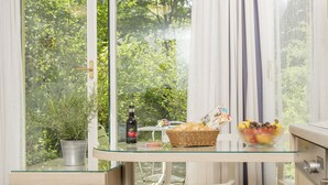 A glass-top table with a bottle, a basket, and a bowl of fruit. - Appartements Ferchergasse (Vienna)