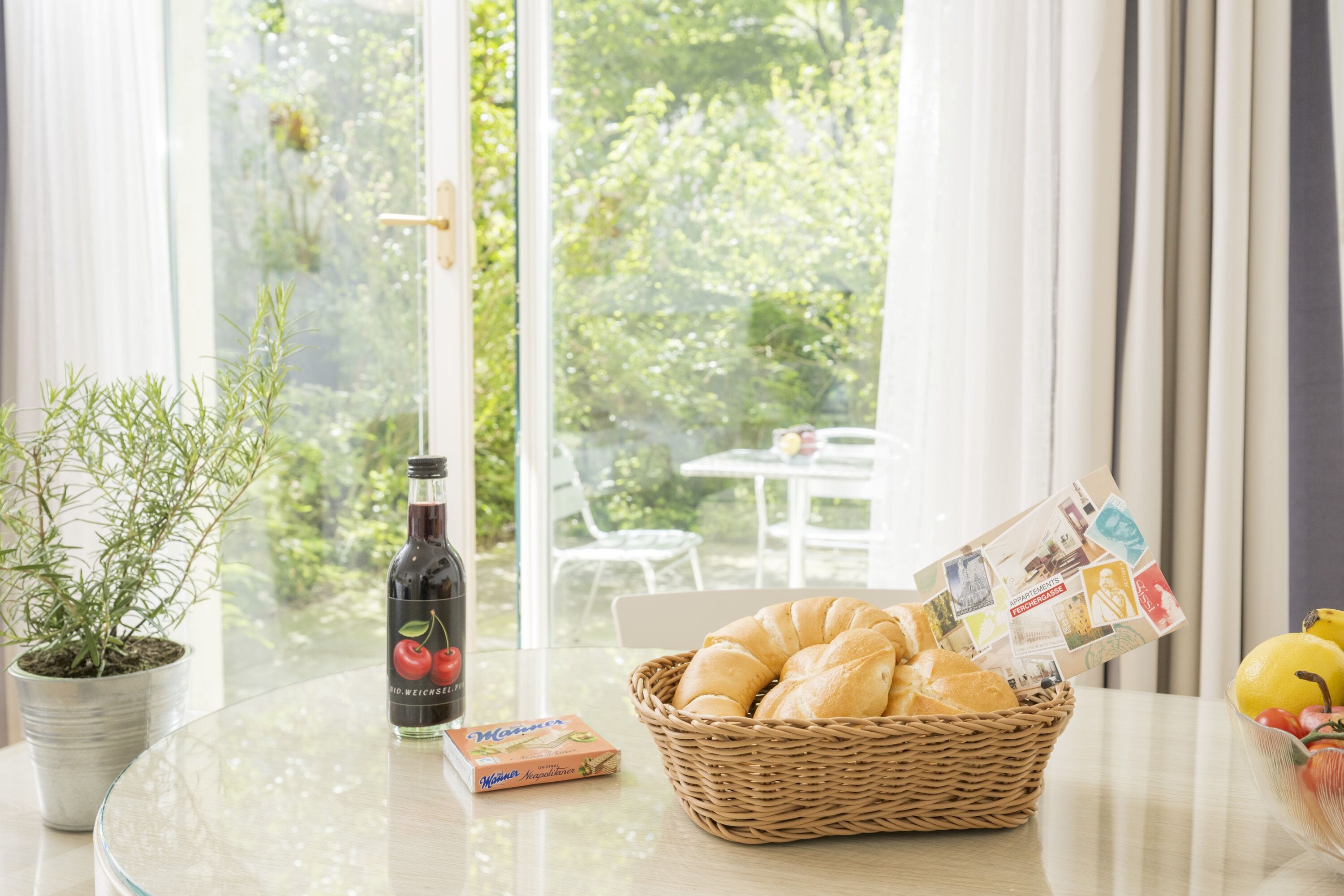 Ein Tisch mit einer Flasche, einem Brotkorb und einer Obstschale.