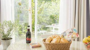 Ein Tisch mit einer Flasche, einem Brotkorb und einer Obstschale.