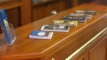 A wooden reception desk with a brass handle, a blue informational stand, and several magazines or brochures on the surface.