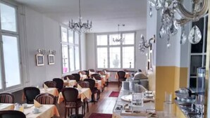 Ein Restaurant mit mehreren Tischen und Stühlen, einer langen Theke mit Registrierkasse und einer Kristallleuchtre.
