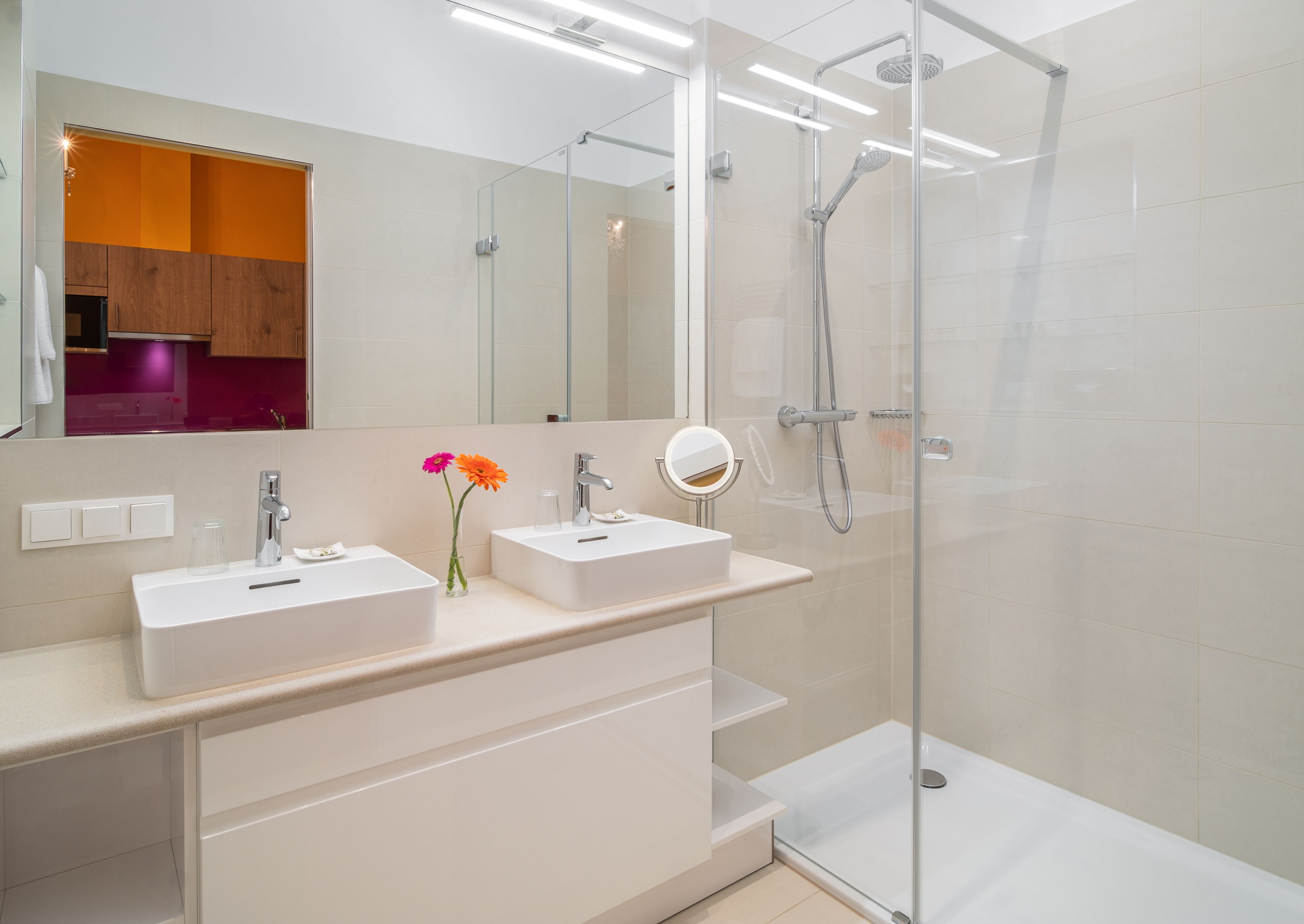 A modern bathroom with two sinks, a shower, and a glass-enclosed shower area.