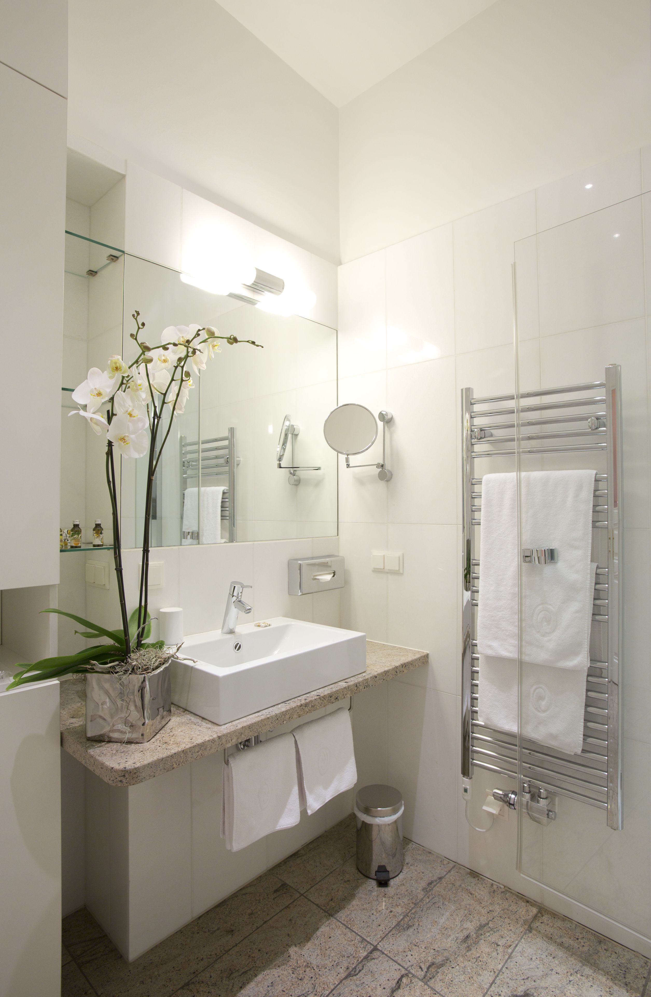 A modern bathroom with a white sink, a glass shower enclosure, and a mirror above the sink.