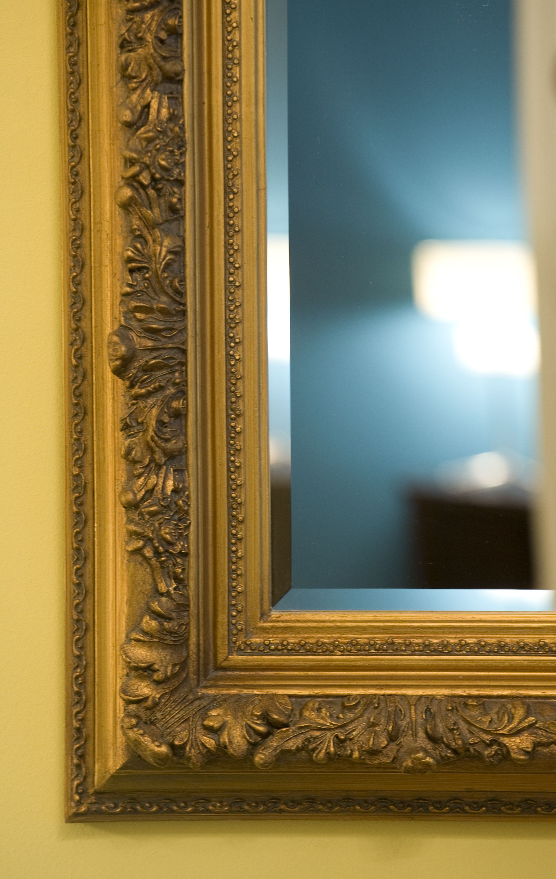 Uno specchio con cornice dorata e decorazioni floreali elaborate.
