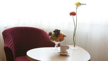 A round table with a fruit bowl, a cup, and a vase with a single flower.