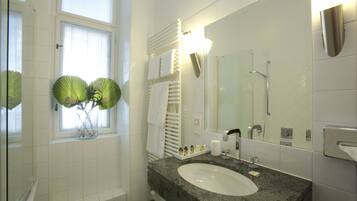 A bathroom with a large mirror, a sink, and a window with blinds.