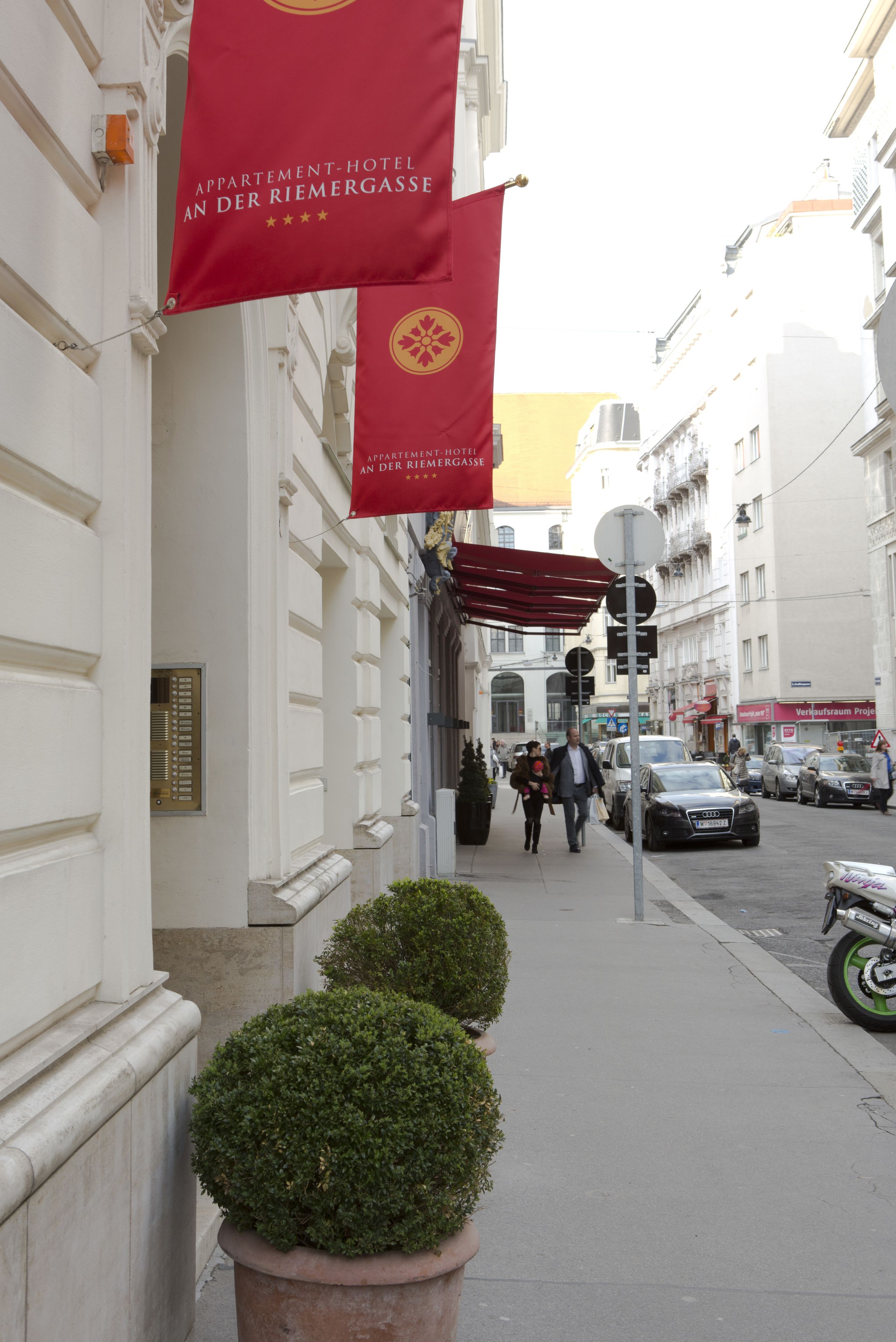 Une rue bordée de drapeaux, de plantes en pot et de piétons.