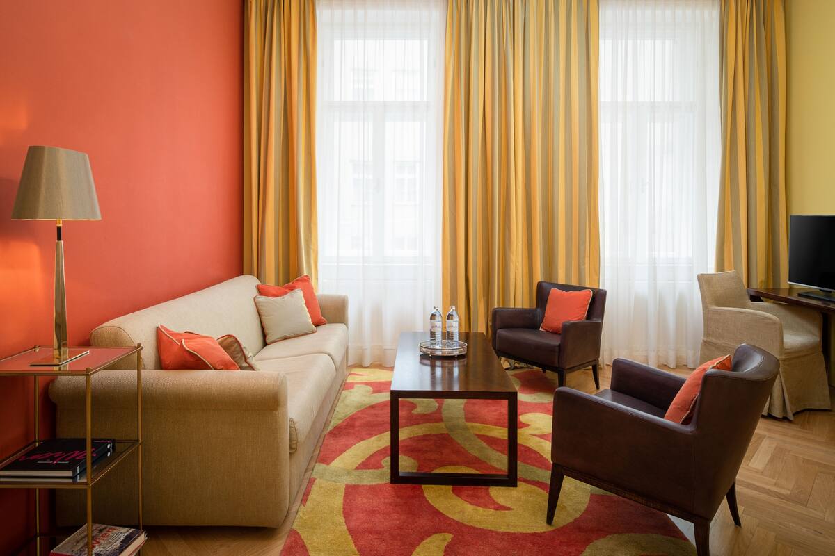 A living room with a sofa, two armchairs, a coffee table, a lamp, and a TV.