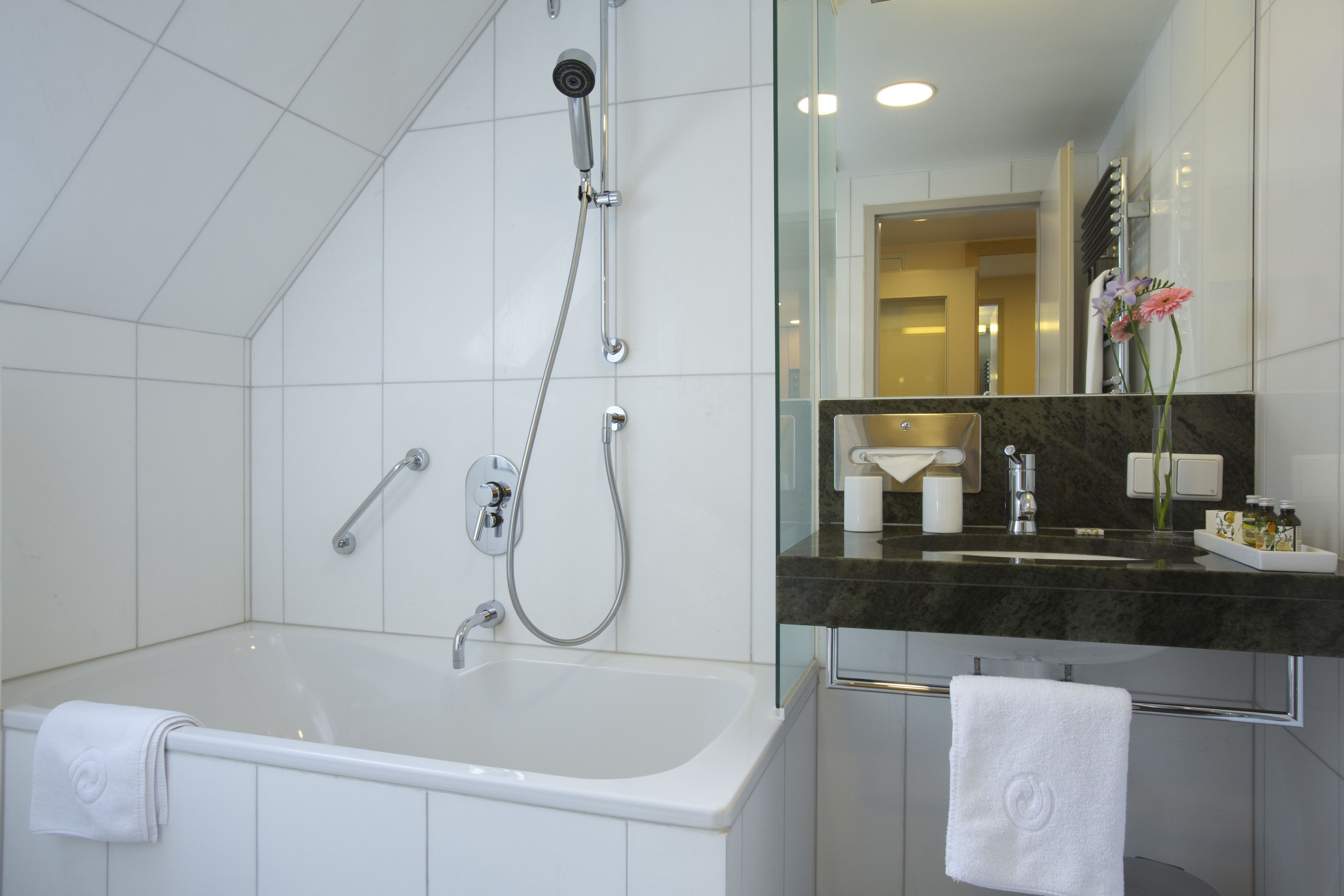 A modern bathroom with a bathtub, a shower, a vanity with a sink, and a mirror.