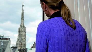 A person in a purple sweater looking out at a tall, Gothic-style church with intricate architecture.