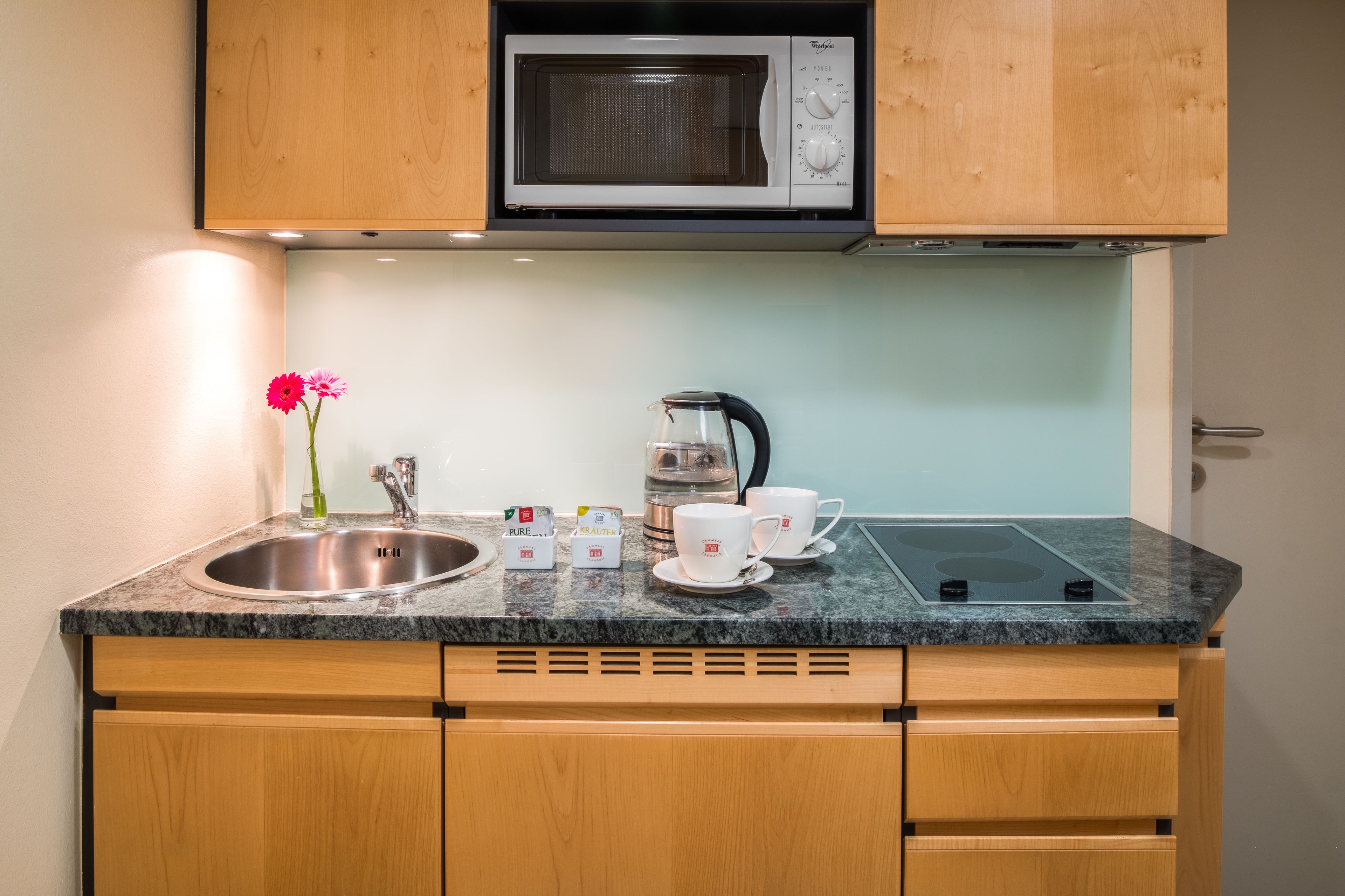 Cocina compacta con microondas integrado, pileta, hervidor y cafetera.