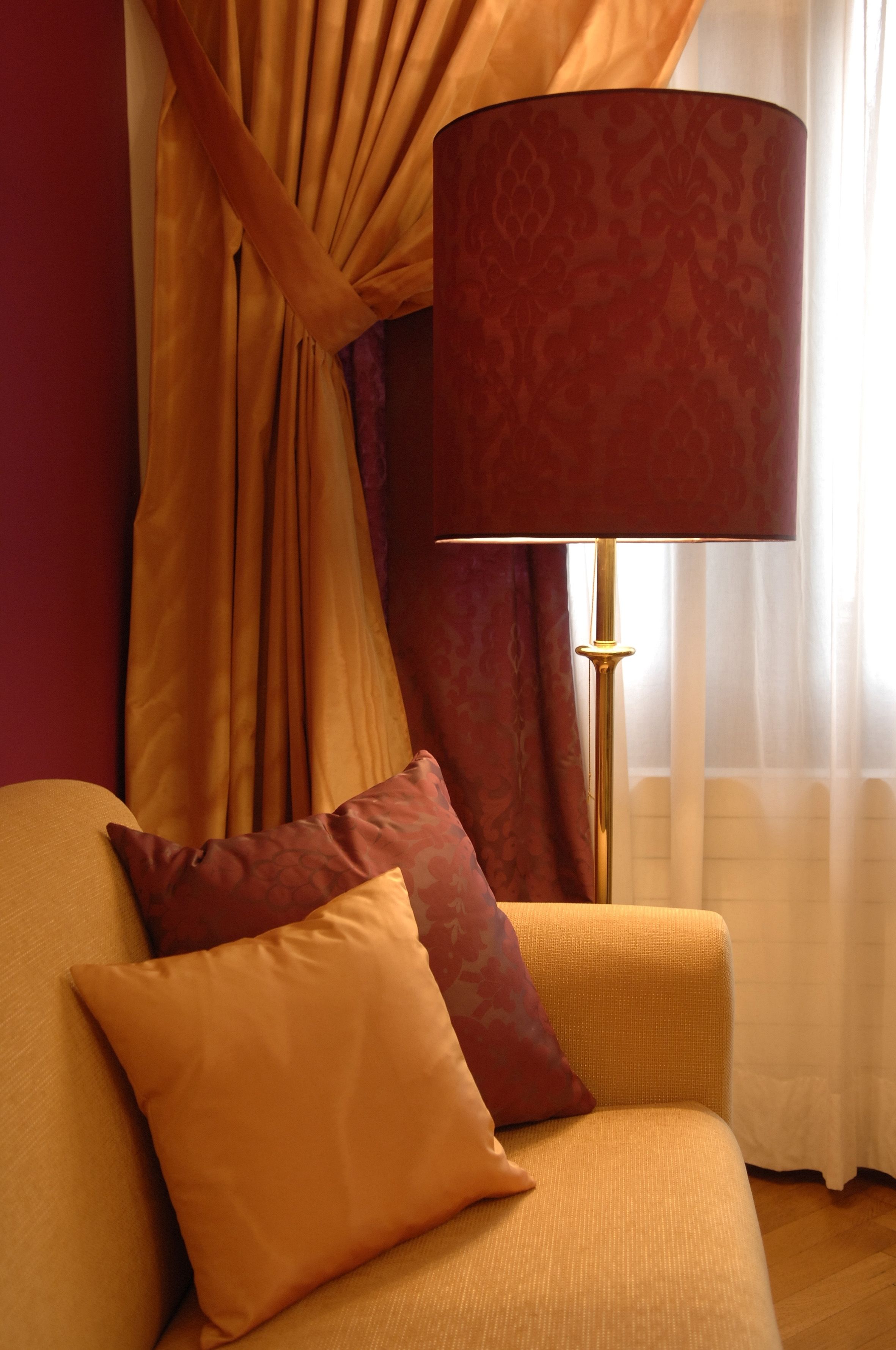 Une pièce avec un canapé, deux coussins, une lampe et des rideaux.