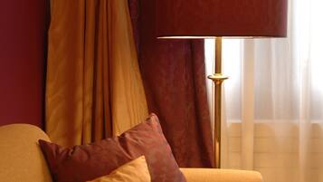 Une pièce avec un canapé, deux coussins, une lampe et des rideaux.