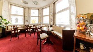 A corner dining area with marble walls, large windows, and a fruit basket on a wooden table. - Hotel Pension Dormium (Vienna)